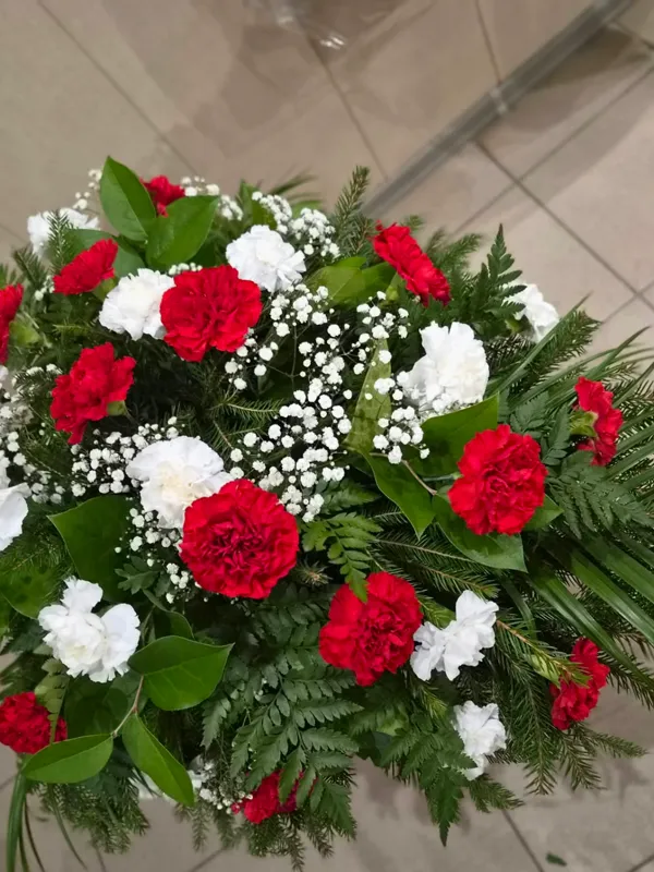 Sēru štrauss ar sarkanām un baltām neļķēm un palmu lapām
